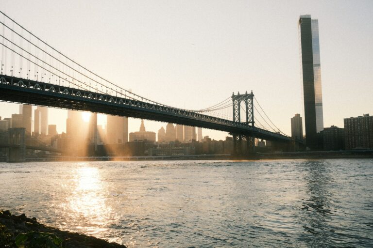 The manhattan bridge spans a shimmering waterway.